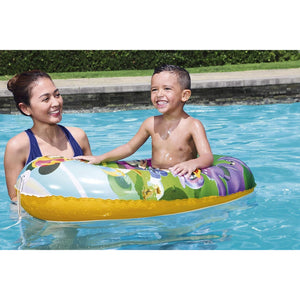 Enfant installé dans le bateau gonflable Mickey dans une piscine, accompagné d'un adulte