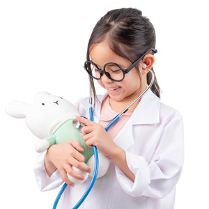 Enfant en blouse blanche jouant au docteur avec le stéthoscope du kit en bois