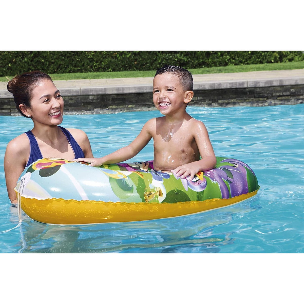 Enfant installé dans le bateau gonflable Mickey dans une piscine, accompagné d'un adulte
