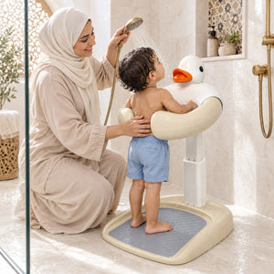 Bébé debout sur la base antidérapante, appuyé sur l'arceau du canard pendant que sa maman le douche