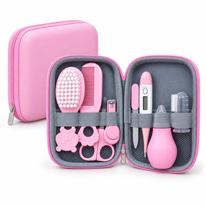 Kit de soin bébé rose ouvert : brosse, peigne, thermomètre, mouche-bébé, coupe-ongles et ciseaux