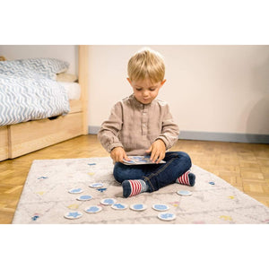 Enfant de 2 ans qui joue au jeu Nathan Couleurs et formes assis sur un tapis