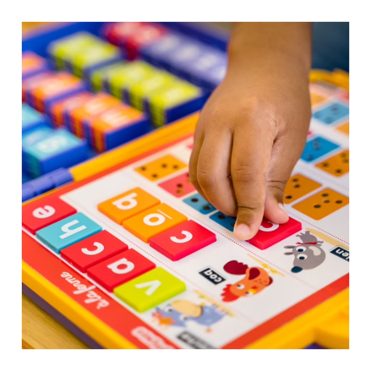 Enfant composant un mot avec les jetons-lettres du jeu Nathan J'apprends à lire