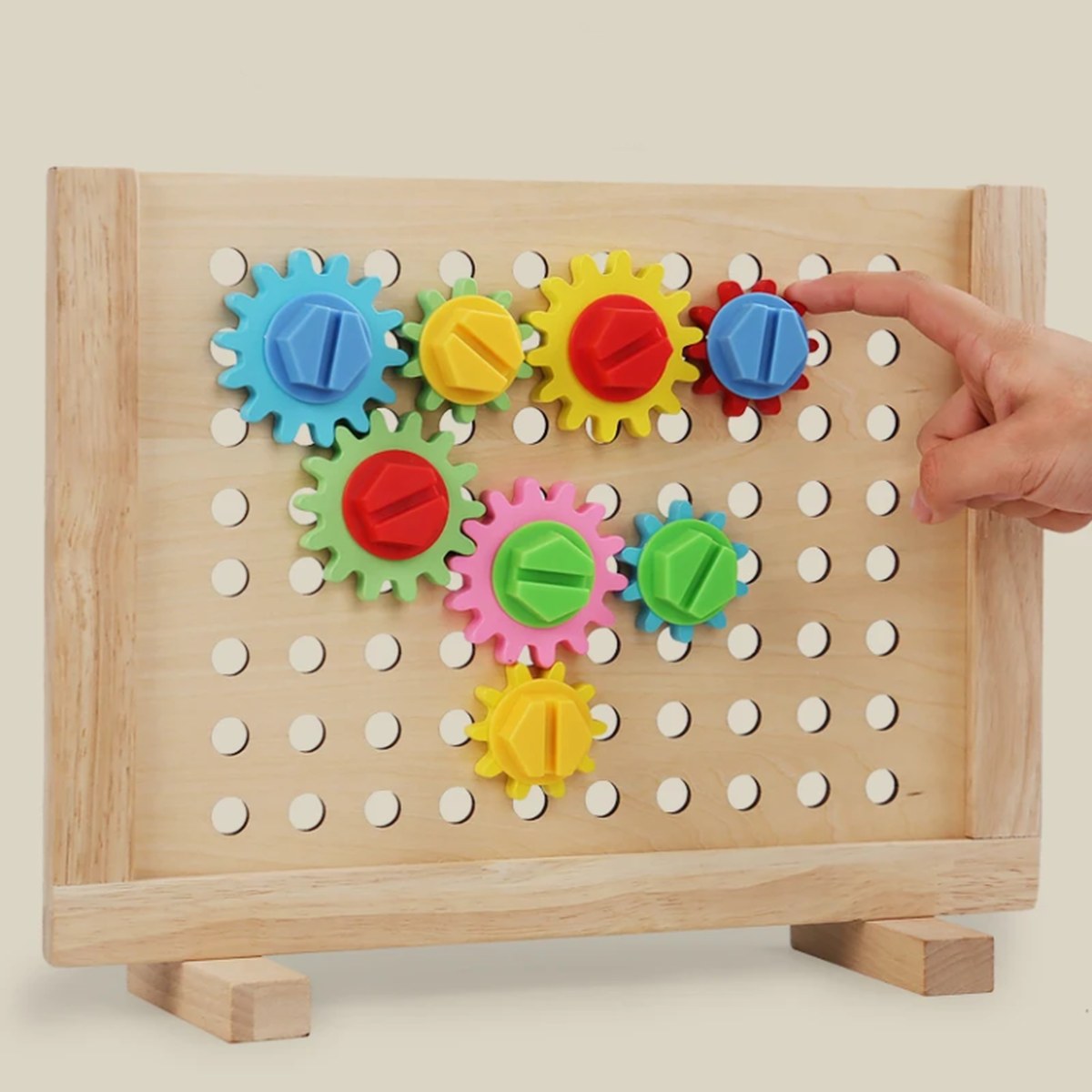 Enfant faisant tourner les engrenages colorés du panneau en bois Montessori