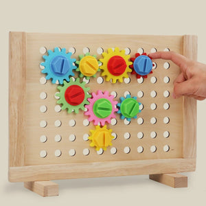 Enfant faisant tourner les engrenages colorés du panneau en bois Montessori