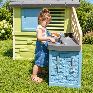 Enfant jouant à la cuisine d'été de la Maison Pretty Smoby : évier, robinet et plaques de cuisson
