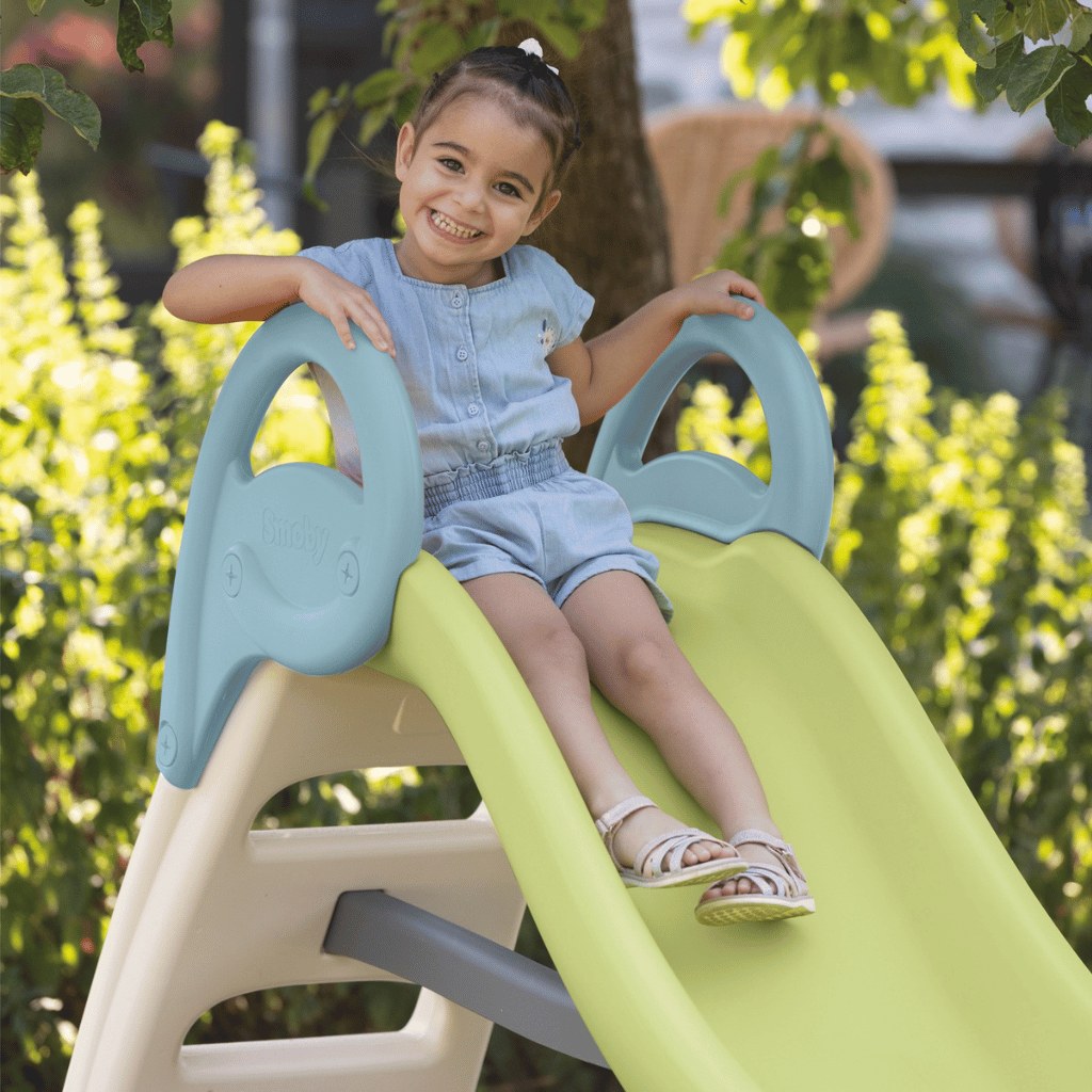 Enfant assis en haut du toboggan Smoby Funny, mains sur les rampes bleues