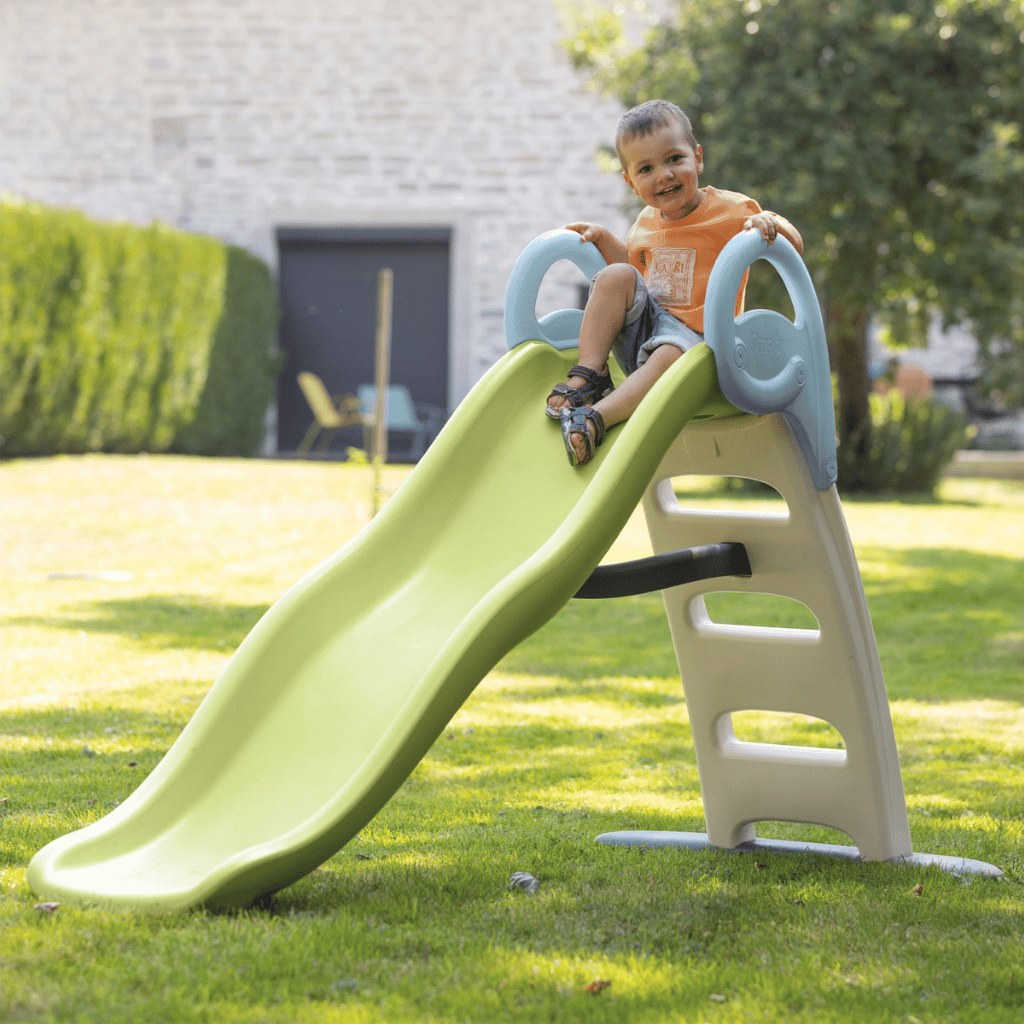 Toboggan Smoby Funny installé sur la pelouse d'un jardin avec un enfant