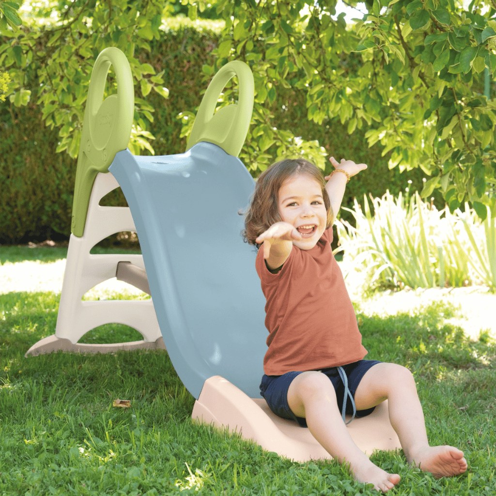 Enfant qui glisse sur le toboggan Smoby KS bleu dans un jardin