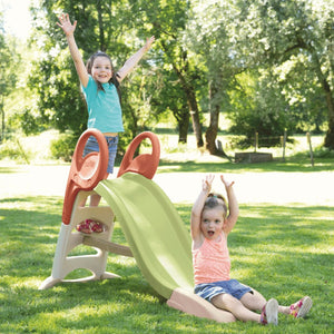 Deux enfants jouent sur le toboggan Smoby KS dans un jardin