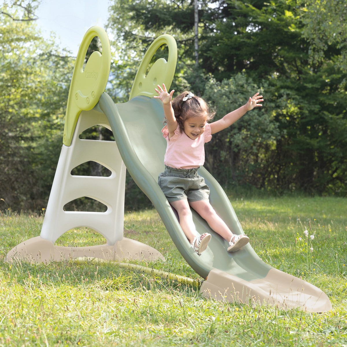 Enfant bras levés sur le toboggan Smoby XL installé sur une pelouse