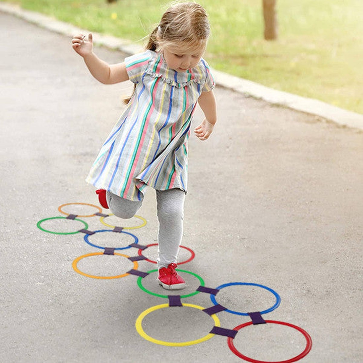 Enfant qui saute sur le parcours de marelle à cerceaux Twister Hopscotch dans le jardin