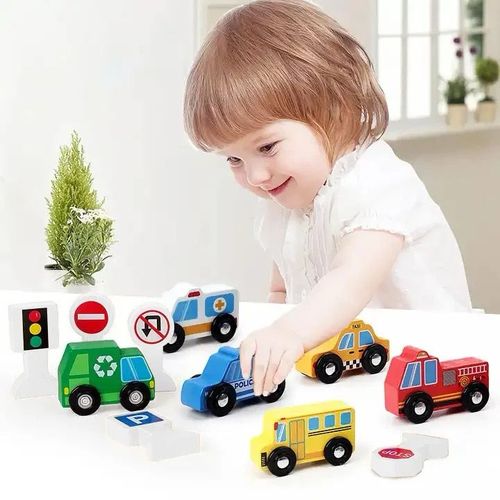 Enfant jouant avec les véhicules en bois et les panneaux de signalisation sur une table