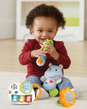 Bébé jouant avec le hochet grenouille, la peluche hippo et le piano du coffret VTech