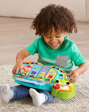 Jeune enfant assis explorant les pages de l'imagier tortue VTech