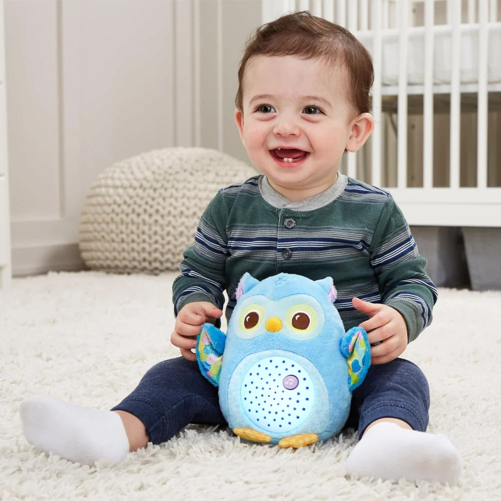 Petit garçon souriant tenant la peluche Lumi chouette bleu VTech