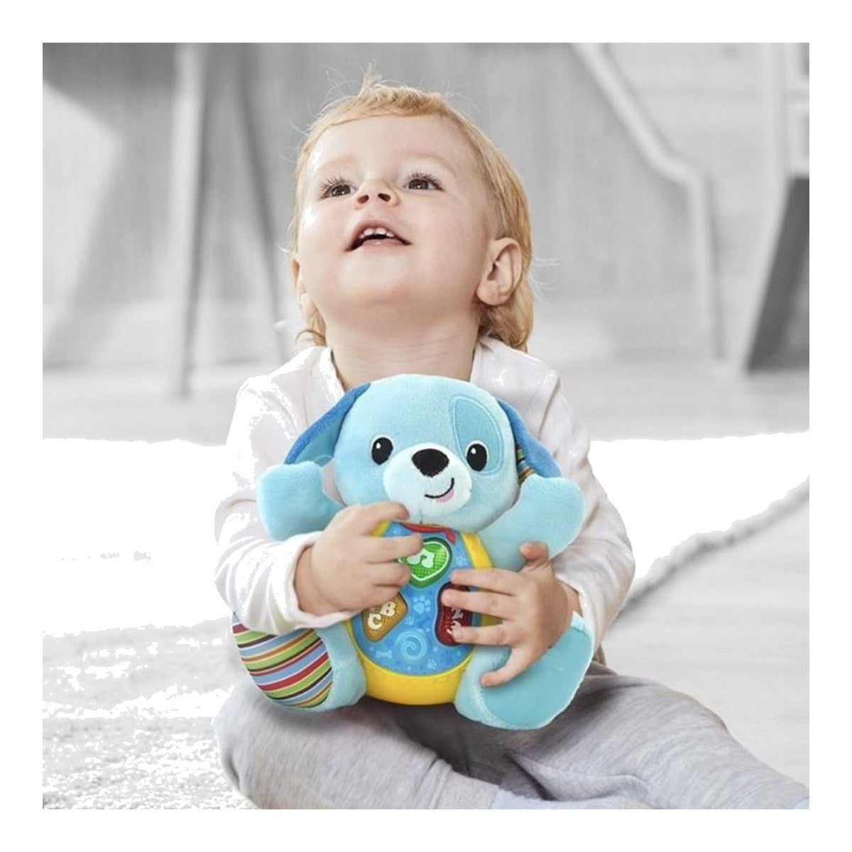 Bébé assis qui serre le doudou chien musical Winfun dans ses bras