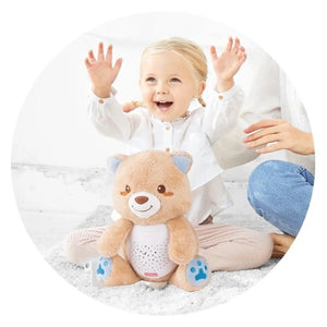 Enfant jouant avec l'ourson veilleuse Winfun posé sur un tapis